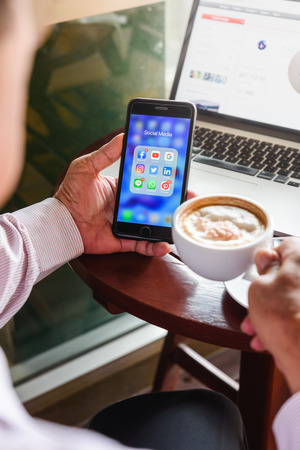 BANGKOK, THAILAND- 23th August 2019 : Hands of an old man use Iphone 7 plus with social media application icon of facebook, youtube, google search, instagram, twitter, linkedin, line whatsapp, and pinterest in a cafeのeditorial素材
