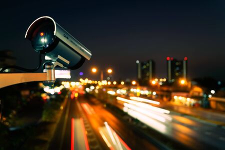 CCTV, Surveillance camera operating in city watching traffic road at nightの写真素材