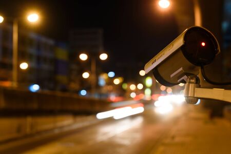 CCTV, Surveillance camera operating in city watching traffic road at nightの写真素材