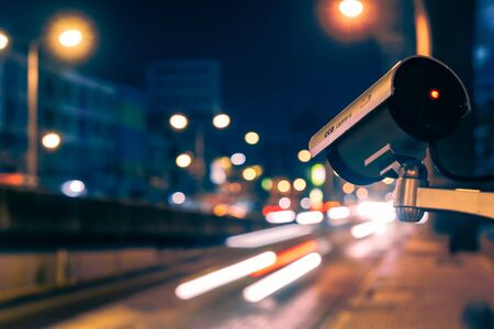 CCTV, Surveillance camera operating in city watching traffic road at nightの写真素材