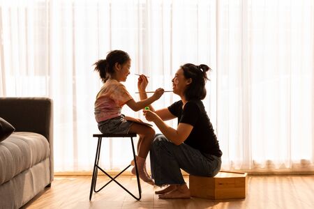 Little daughter play facial painting with mother in afternoonの写真素材