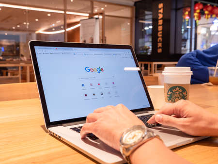 BANGKOK, THAILAND- 01 February 2020 : Hands of man use macbook pro open google searching on internet in starbucks coffee shopのeditorial素材