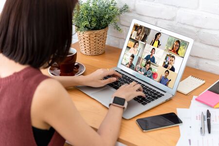 Woman use laptop with screen of video conference meeting  with 9 other people, work from home...
