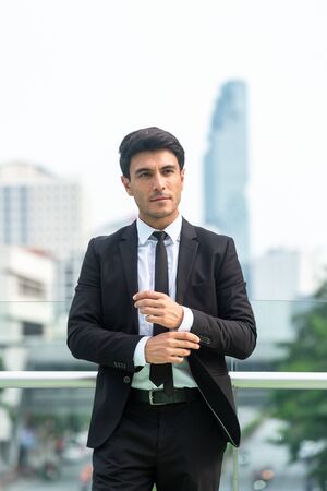 Portrait of confident businessman in black suit in city finding job during crisisの写真素材