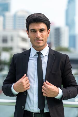 Portrait of confident businessman in black suit in city finding job during crisisの写真素材