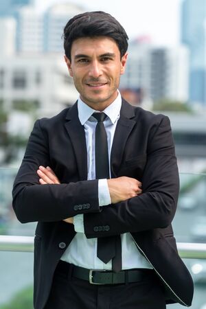 Portrait of confident businessman in black suit in city finding job during crisisの写真素材