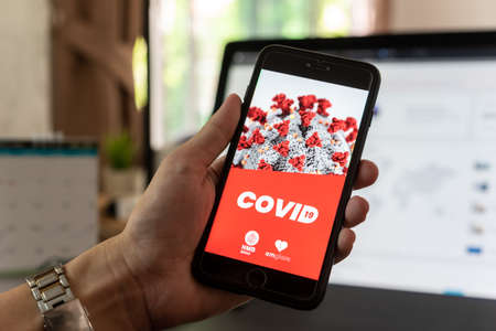 NONTABURI, THAILAND - May 21st, 2020 : Hands of man show screen of iphone with application of Covid-19 Trackerのeditorial素材