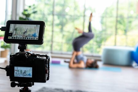 Video camera recording young master yoga performing shoulder stand with monitorの写真素材