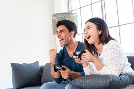 Gaming time in family, couple enjoy playing games together at home after work time, way to relax duting lock downの写真素材
