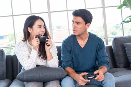 Gaming time in family, couple enjoy playing games together at home after work time, way to relax duting lock down, girlfriend win boyfriendの写真素材
