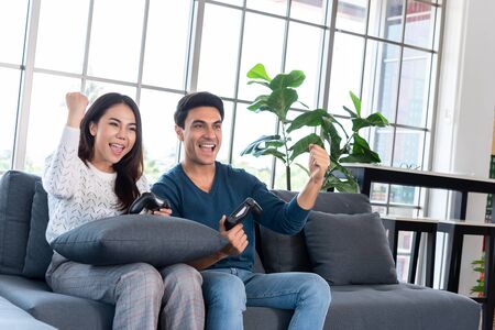 Gaming time in family, couple enjoy playing games together at home after work time, way to relax duting lock down, winning game togetherの写真素材