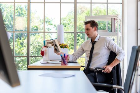 Stress businessman fired from work looking at his family photo frame about to leave the officeの写真素材