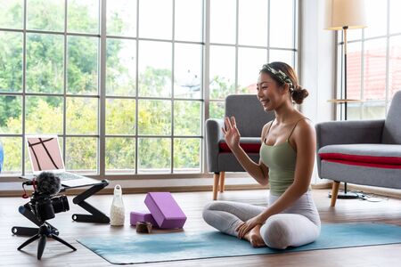 Young yoga master recording video content for her online course with camera and laptopの写真素材