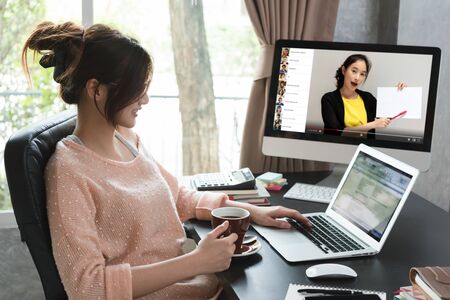 Online course attended by woman at home and working at the same time, learning at home with 10 other peopleの写真素材