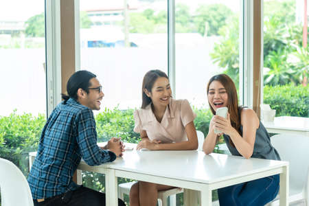 Three friends meet and see each other use smartphone play social media togetherの写真素材