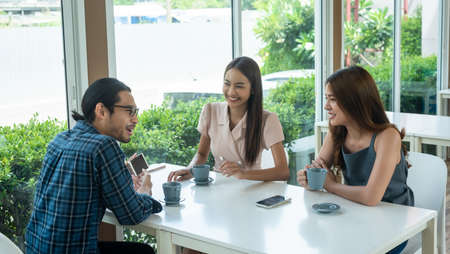 Three friends meet and see each other use smartphone play social media togetherの写真素材