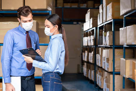 Two staff worker at warehouse wear surgical mask during work hour as new normal conceptの写真素材