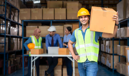 Warehouse worker holding a big parcel box working with his teamの写真素材