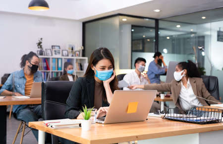 Woman business worker sending document to co-worker wearing flu mask in office show new normal lifestyleの写真素材