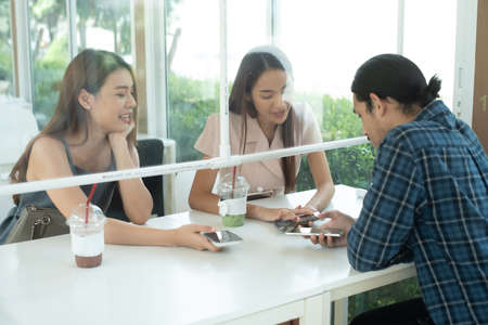 Group of three people see each other in cafe with plastic partition for social distanccingの写真素材