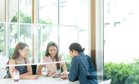 Group of three people see each other in cafe with plastic partition for social distanccingの写真素材