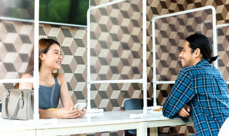 Couple in restaurant with plastic partition seperate for social distancing in new normal life style