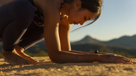 Young good looking woman perform yoga pose on mountain with sun light during sunsetの写真素材