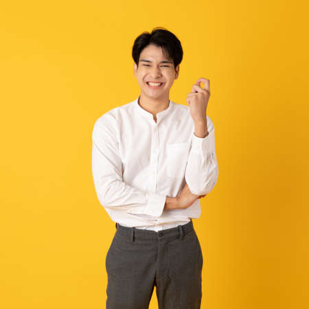 Good looking teenage asian man with laugh isolate on yellow backgroundの写真素材