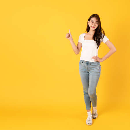 Smiling asian woman white shirt on yellow background with thumbs up show appreciateの写真素材