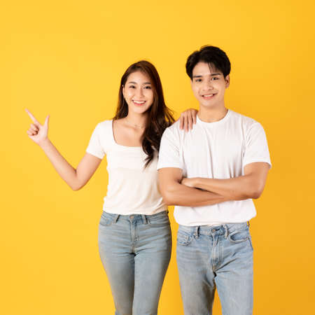 Couple of teenage asian boy and girl together isolate on yellow background pointing and surpriseの写真素材