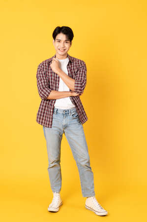 Smile happy asian man wearing scottish shirt with jeans isolated on yellow background
