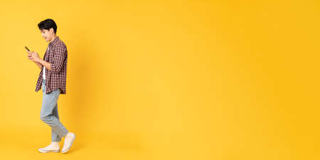 Smile happy asian man wearing scottish shirt with jeans isolated on yellow background using...