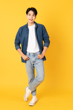 Smile happy asian man wearing shirt with jeans and laughing isolated on yellow backgroundの写真素材