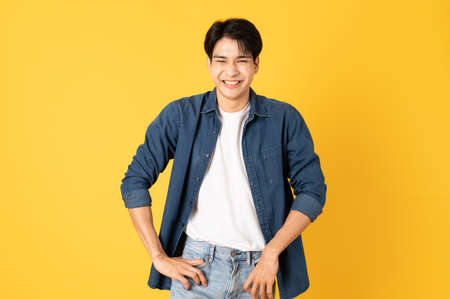 Smile happy asian man wearing shirt with jeans and laughing isolated on yellow backgroundの写真素材