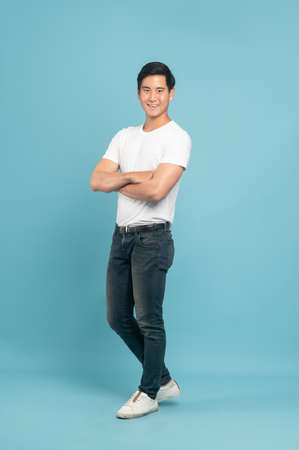 Nice asian guy in white t-shirt and jeans isolated on blue backgroundの写真素材