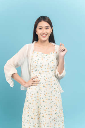 Beautiful young asian woman in white dress with flower pattern isolated on blue backgroundの写真素材