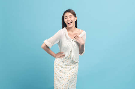 Beautiful young asian woman in white dress with flower pattern  isolated on blue backgroundの写真素材