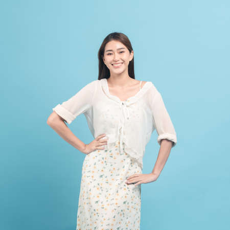Beautiful young asian woman in white dress with flower pattern  isolated on blue backgroundの写真素材