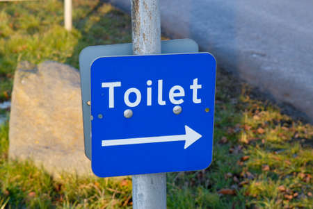 Blue sign with a white text that points towards public toiletの写真素材