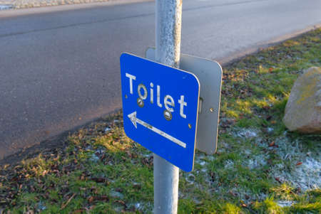 Blue sign with white text that points towards public toilet