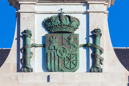 Spanish coat of arms (Spain) forged in rusty bronze on stone background and blue skyのeditorial素材