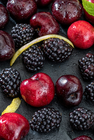 Delicious and appetizing fruits of the forest, blackberries and fresh and raw cherries. On dark background.の写真素材