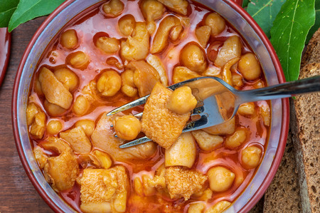 Chickpeas with tripe in clay pot. Aerial (top) view. On wooden background.