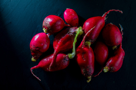 Ecological radishes (red radishes - rabanites) of intense red color. Close-up on black background.の写真素材