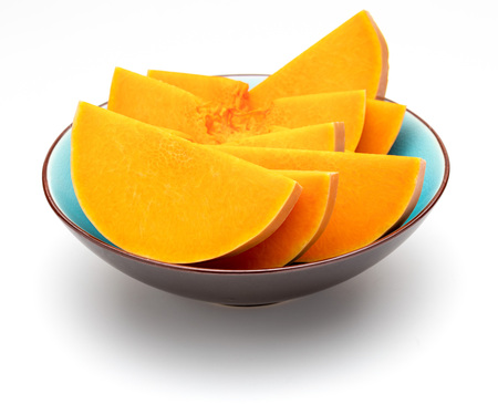 Sliced pumpkin in blue bowl. Isolated on white background.の写真素材