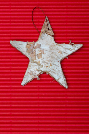 Beautiful star of birch bark on red corrugated cardboard background. Ready for Christmas greeting.の写真素材
