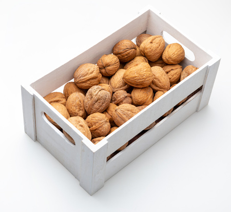 Walnuts in wooden box. Rustic appearance. Isolated on white background.の写真素材