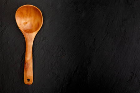 Wooden spoon on black slate background with texture. Space to insert your text here. Letter for restaurants. (Food concept of spoon, pot).の写真素材