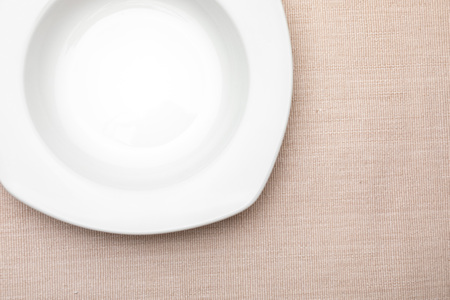 Empty white plate. On delicate beige tablecloth. Concept to include your food and your text.の写真素材