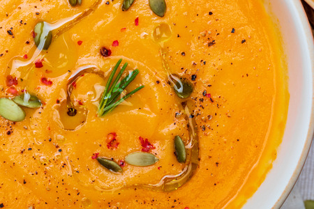 Close-up of a delicious pumpkin cream. Home and rustic appearance. Includes fresh pumpkin, seeds and rye bread. Aerial view.の写真素材